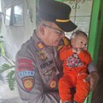 Kapolsek Diwek Iptu Edy Widyono saat menggendong bayi./bongkah.id/Karimatul Maslahah/