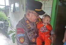 Kapolsek Diwek Iptu Edy Widyono saat menggendong bayi./bongkah.id/Karimatul Maslahah/