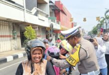 Kasatlantas Polres Mojokerto Kota AKP Mulyani membagikan helm kepada pengendara yang tertib berlalulintas di jalan raya Majapahit Kota Mojokerto, Selasa (18/2/2025).