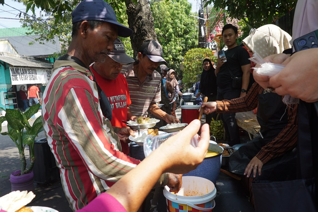 1000738833 Tukang becak dan pengguna jalan antre mengambil sarapan gratis yang disediakan warga lingkungan Jalan Dokter Setiabudi Jombang. Bongkah.id/Karimatul Maslahah/
