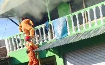 Petugas damkar Jember berusaha menyelamatkan penghuni dan memadamkan api yang membakar rumah kos, Selasa (3/6/2025). Bongkah.id/Muhammad Hatta/