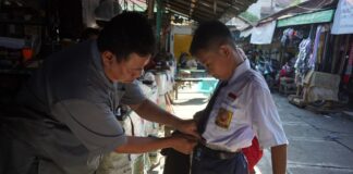 Ismail saat menerima pelanggan jahit seragam di pasar tanjung anyar, Kota Mojokerto./bongkah.id/Karimatul Maslahah/