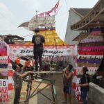Aden dan warga sekitar saat menempelkan kain perca bekas di gapura garuda./bongkah.id/Karimatul Maslahah/