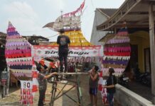 Aden dan warga sekitar saat menempelkan kain perca bekas di gapura garuda./bongkah.id/Karimatul Maslahah/