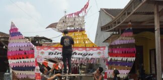 Aden dan warga sekitar saat menempelkan kain perca bekas di gapura garuda./bongkah.id/Karimatul Maslahah/