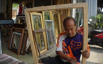 Romy saat mengamplas bingkai kayu di halaman tokonya./bongkah.id/Karimatul Maslahah/