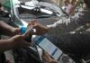 Juru parkir melayani pembayaran non tunai menggunakan QRIS dalam sistem parkir digital di Kota Surabaya.