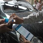 Juru parkir melayani pembayaran non tunai menggunakan QRIS dalam sistem parkir digital di Kota Surabaya.