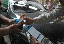 Juru parkir melayani pembayaran non tunai menggunakan QRIS dalam sistem parkir digital di Kota Surabaya.