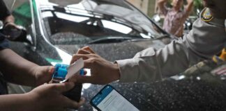 Juru parkir melayani pembayaran non tunai menggunakan QRIS dalam sistem parkir digital di Kota Surabaya.