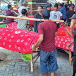 Warga Desa Pagerngumbuk Sidoarjo mengarak tumpeng dan hasil bumi di atas amben bambu saat tradisi ruwat desa.