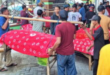 Warga Desa Pagerngumbuk Sidoarjo mengarak tumpeng dan hasil bumi di atas amben bambu saat tradisi ruwat desa.
