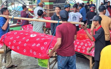 Warga Desa Pagerngumbuk Sidoarjo mengarak tumpeng dan hasil bumi di atas amben bambu saat tradisi ruwat desa.
